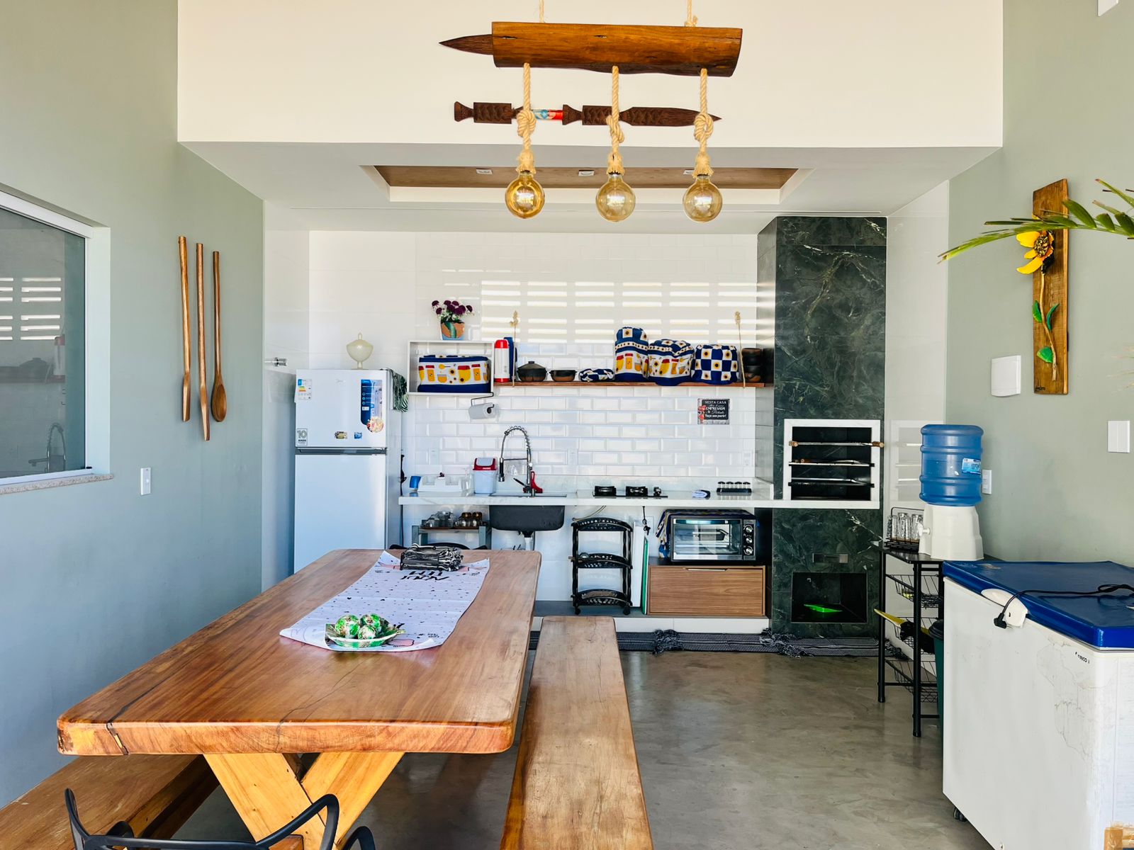 Espaço gourmet com mesa grande, churrasqueira e cozinha